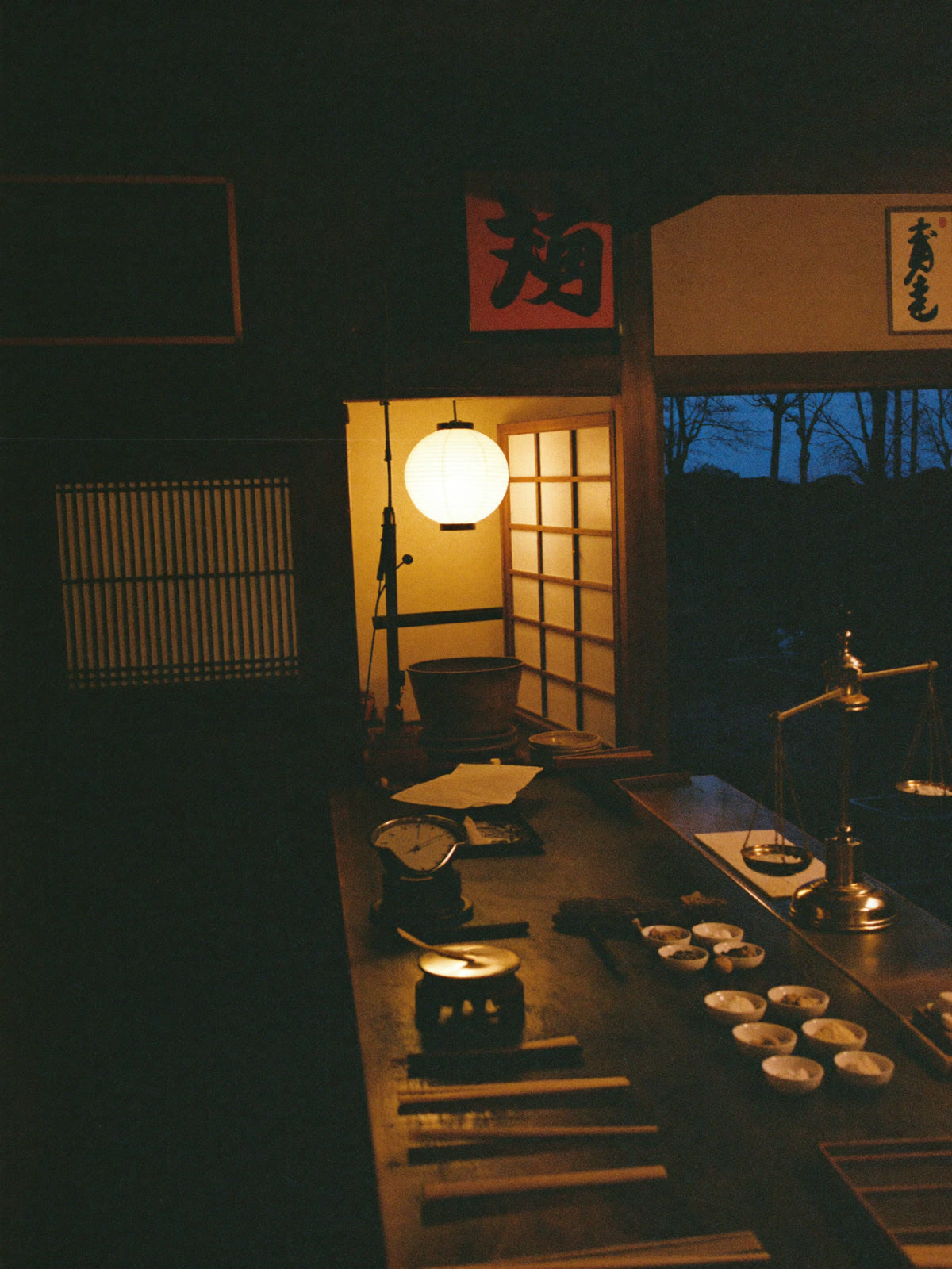 The KEMURI workshop at dusk — lantern light over the blending bench